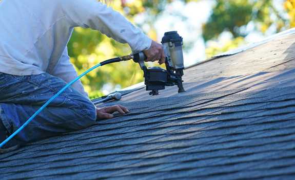 roofer installing shingles on asphalt roof